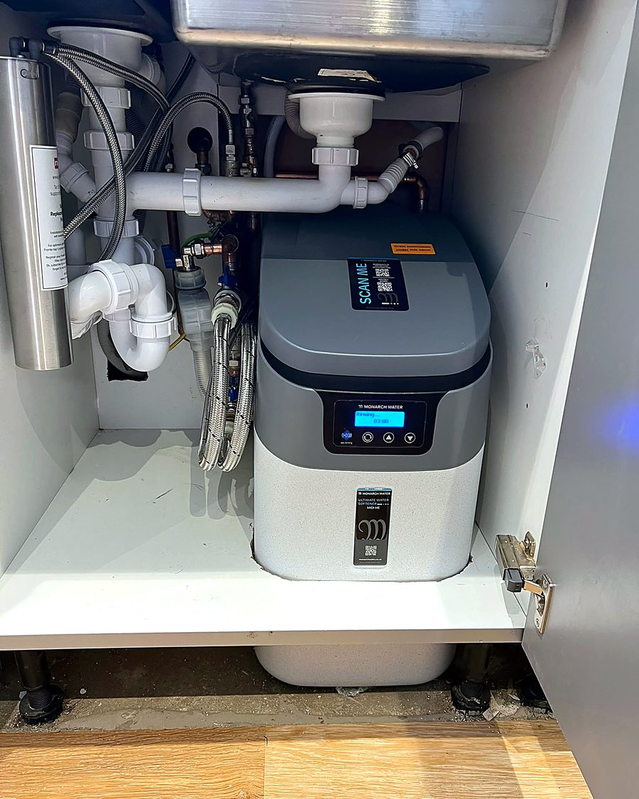 A water softener fitted under a kitchen sink